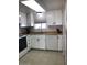 A well-lit kitchen featuring white cabinets, a double sink, and neutral tile flooring at 2400 N 71St St # T, Scottsdale, AZ 85257