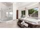 Bright bathroom featuring a soaking tub with a view, glass shower, and marble columns at 7929 N 55Th St, Paradise Valley, AZ 85253