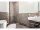 Rustic bathroom featuring textured stone-look walls, a minimalist sink, and a modern toilet at 7929 N 55Th St, Paradise Valley, AZ 85253
