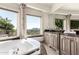 Luxurious bathroom showcasing a jetted tub with marble surround and a vanity offering scenic views at 7929 N 55Th St, Paradise Valley, AZ 85253