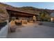 Covered patio with an outdoor kitchen, fireplace, and dining area, providing a luxurious outdoor living experience with mountain views at 7929 N 55Th St, Paradise Valley, AZ 85253