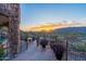Balcony with iron railing overlooking the city at sunset with potted plants, stone columns, and an outdoor dining set at 7929 N 55Th St, Paradise Valley, AZ 85253