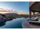 Infinity pool with chaise lounges overlooks the city with mountain views and a tranquil sunset at 7929 N 55Th St, Paradise Valley, AZ 85253