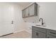 Modern laundry room with gray cabinets, quartz countertops, and tile floors at 17455 W El Caminito Dr, Waddell, AZ 85355