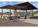 This outdoor kitchen features a built-in grill, counter space, dining table, and shade in a community outdoor common area at 17636 W Pierson St, Goodyear, AZ 85395