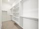 This walk-in closet features adjustable shelving, a hanging rack and neutral carpet at 17636 W Pierson St, Goodyear, AZ 85395