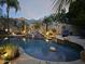 Tranquil backyard pool featuring a rock waterfall, desert landscaping, and ambient lighting for relaxed outdoor living at 2611 W Trapanotto Rd, Phoenix, AZ 85086