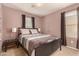 Spacious bedroom with striped bedding, nightstand, and large windows at 45707 W Barbara Ln, Maricopa, AZ 85139