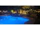Blue illuminated pool at night with rock waterfall feature at 45707 W Barbara Ln, Maricopa, AZ 85139