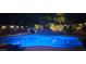 Blue illuminated pool at night with rock waterfall feature at 45707 W Barbara Ln, Maricopa, AZ 85139