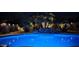 Blue illuminated pool with a rock waterfall feature at night at 45707 W Barbara Ln, Maricopa, AZ 85139