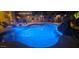 Blue illuminated pool at night with patio furniture at 45707 W Barbara Ln, Maricopa, AZ 85139
