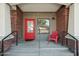 Charming front porch featuring brick accents, a vibrant red door, and cozy outdoor seating at 475 N 9Th St # 115, Phoenix, AZ 85006