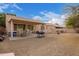 View of the backyard showing a covered patio with outdoor dining, a barbecue grill, and low-maintenance gravel landscaping at 11606 W Laurelwood Ln, Avondale, AZ 85392