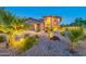 Two-story home featuring a circular driveway, a manicured lawn, desert landscaping and warm exterior lighting at 12015 S Tuzigoot Dr, Phoenix, AZ 85044