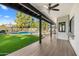 Covered patio with wood-look tile flooring, overlooking a sparkling pool and grassy yard at 12286 N 86Th Pl, Scottsdale, AZ 85260