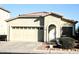Tan house with a two-car garage and landscaping at 13915 N 132Nd Ln, Surprise, AZ 85379