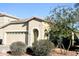 Tan house with a two-car garage and landscaping at 13915 N 132Nd Ln, Surprise, AZ 85379