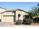 Tan house with a two-car garage and landscaping at 13915 N 132Nd Ln, Surprise, AZ 85379