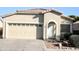 Tan house with a two-car garage and landscaping at 13915 N 132Nd Ln, Surprise, AZ 85379