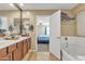 Bathroom with double sinks, a soaking tub, and view into bedroom at 1923 N Cocoa Ct, Casa Grande, AZ 85122