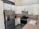 Bright kitchen features white cabinets, stainless steel appliances, and modern gray wood-look flooring at 6703 W Linda Ln, Chandler, AZ 85226