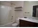 Bright bathroom featuring a tub with white tile surround, floating shelves, and a vanity with dark wood cabinets at 38133 W Vera Cruz Dr, Maricopa, AZ 85138