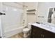 Bathroom features a tiled shower-tub combo, floating shelves, and a wooden vanity with a white countertop at 38133 W Vera Cruz Dr, Maricopa, AZ 85138