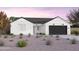 One-story home with white siding, a black garage door, and landscaping at 1304 W Golden Ore Pass, Apache Junction, AZ 85120