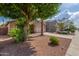 Well-maintained house featuring a two-car garage, xeriscaping, a mature shade tree and a palm tree at 14995 W Desert Hills Dr, Surprise, AZ 85379
