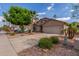 Well-maintained house featuring a two-car garage, xeriscaping, mature shade trees and a palm tree at 14995 W Desert Hills Dr, Surprise, AZ 85379