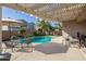 Relaxing pool area with pergola, patio furniture, and palm trees at 14995 W Desert Hills Dr, Surprise, AZ 85379
