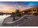 Stunning sunset view of backyard oasis with covered patio, lake access, and mature landscaping at 42585 W Heavenly Pl, Maricopa, AZ 85138