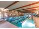 Bright indoor pool area with wood beam ceilings and lots of natural light from the surrounding windows and exit doors at 42585 W Heavenly Pl, Maricopa, AZ 85138