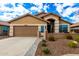 Tan house with a two-car garage and nicely landscaped yard at 20472 N 90Th Ln, Peoria, AZ 85382