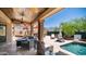 Inviting covered back patio featuring lounge seating, bar area, and a refreshing pool, perfect for outdoor relaxation at 4119 S Las Villa Way, Gold Canyon, AZ 85118