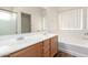Bathroom with double vanity, tub, and wood cabinets at 4233 E Colonial Dr, Chandler, AZ 85249