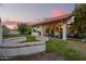 Wide backyard with fireplace, stone benches, spacious green lawn, covered patio, and a view of the sunset sky at 3457 E Ellis St, Mesa, AZ 85213
