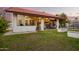 Well-manicured backyard with tiled roof, covered patio, green lawn, privacy wall and orange tree at 3457 E Ellis St, Mesa, AZ 85213
