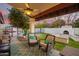 Cozy covered patio with comfortable seating, ceiling fan, and a view of the pool and outdoor fireplace at 3457 E Ellis St, Mesa, AZ 85213