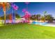 Expansive backyard with a sparkling pool, artificial turf, and dramatic lighting at 4639 E Mountain View Ct, Phoenix, AZ 85028
