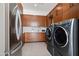 Modern laundry room with stainless steel appliances and wood cabinets at 5825 E Cochise Rd, Paradise Valley, AZ 85253