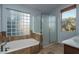 Well-lit bathroom featuring a soaking tub and a glass-enclosed shower at 5951 W Irma Ln, Glendale, AZ 85308