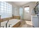 Well-lit bathroom featuring a soaking tub with glass block window, and a glass shower at 5951 W Irma Ln, Glendale, AZ 85308