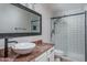 Bathroom with a sleek vanity, vessel sink, and a modern tiled shower with glass doors at 5951 W Irma Ln, Glendale, AZ 85308