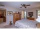 Comfortable bedroom with ceiling fan, wood armoire, and access to bathroom at 9614 N 110Th Ave, Sun City, AZ 85351