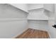 Bright walk-in closet with wood-look tile flooring and ample shelving and hanging space at 4380 N 203Rd Dr, Buckeye, AZ 85396