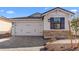 View of the home's garage with stone accents, window with shutters and attractive landscaping at 4419 N 203Rd Ave, Buckeye, AZ 85396
