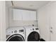 Laundry room features two GE washer and dryer units and white upper cabinets at 659 S Dodge St, Gilbert, AZ 85233