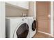 Bright laundry area featuring a front load washer and dryer with ample storage and a convenient utility door at 1449 W Mohawk Ln, Phoenix, AZ 85027